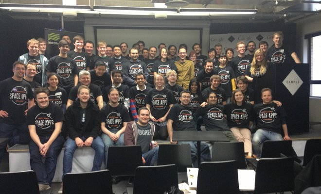 Group of Space Apps participants in a room together posing for a picture wearing black Space Apps t-shirts